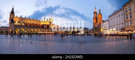 Una foto panoramica della piazza principale di Cracovia Rynek Główny con la Sala dei tessuti, la Basilica di Santa Maria durante la notte con la gente che fa attività di svago Foto Stock