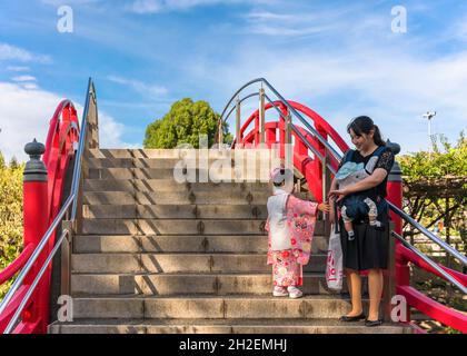 tokyo, giappone - ottobre 26 2019: Bambina in kimono con sua madre e un bambino su un tradizionale ponte taiko bashi rosso nello shintoist Kameido Tenj Foto Stock