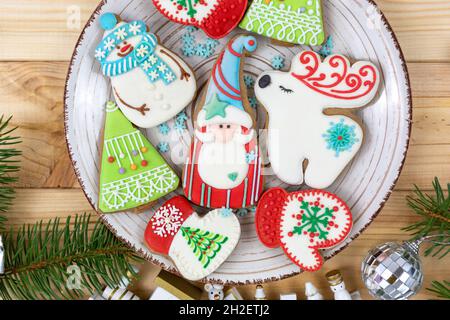 Pani di zenzero di Natale, biscotti su un tavolo naturale di legno accanto ai rami di abete. Fiocchi di neve, pupazzi di neve, cervi, biscotti Babbo Natale. Mockup di nuovo anno Foto Stock