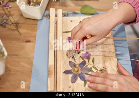 Una donna presenta una composizione. Master class sulla creazione di cornici con Herbarium in tecnica tiffany in vetro colorato. Erbario di diverso essiccato Foto Stock