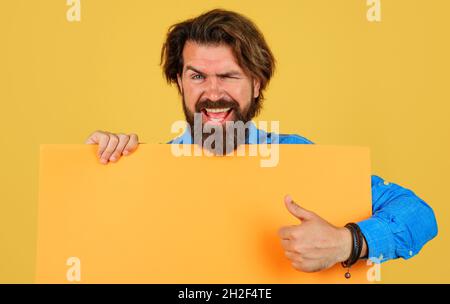 Uomo sorridente con banner pubblicitario vuoto per il tuo testo. Il tipo bearded mostra il pollice in su. Grande vendita e sconto. black friday. Spazio di copia. Foto Stock