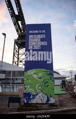 Glasgow, Scozia, Regno Unito. 21 ottobre 2021. FOTO: Finnieston Crane con il cartello ufficiale COP26, BENVENUTO ALLA CONFERENZA ONU sui CAMBIAMENTI CLIMATICI UK 2021. 10 giorni fino all'inizio della COP26. Il sito COP26 mostra strutture temporanee costruite per metà sul terreno dello Scottish Event Campus (SEC), precedentemente noto come Scottish Exhibition and Conference Centre (SECC). Le recinzioni di sicurezza con un 'anello di acciaio' incapsulano il sito della conferenza COP26. Le stazioni TVCC con luci di emergenza e altoparlanti sono posizionate in tutto il sito. Credit: Colin Fisher/Alamy Live News Foto Stock