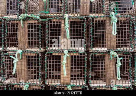 Primo piano di vasi di pesce di aragosta e granchio con reti impilate nel porto Foto Stock