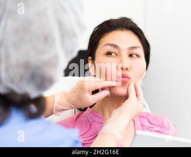 Medico esperto di cosmetologia nella clinica fa una pulizia meccanica del viso una giovane cliente femminile Foto Stock