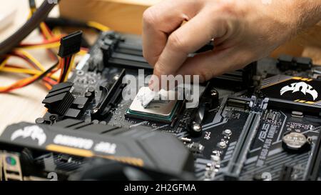 Man applicare pasta termica per l'installazione del microprocessore sulla scheda madre Tuf Gaming b450 Plus. Hardware cpu del computer di manutenzione. Computer di raccolta per Foto Stock