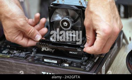 Primo piano di una persona sconosciuta che installa la chiavetta Fury Beast RAM DDR4 sulla scheda madre di un computer professionale per l'estrazione della criptovaluta. Russia, 17.08.2021 Foto Stock