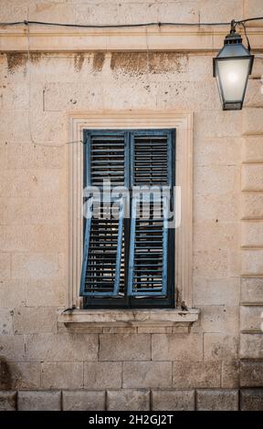 Vecchia finestra con persiane dipinte blu socchiusa. Foto Stock