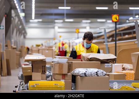 Colonia, Germania. 12 ottobre 2021. Il personale addetto alla consegna dei pacchi smistano e mette i pacchi in un veicolo di consegna presso una base di consegna DHL Deutsche Post. Credit: Rolf Vennenbernd/dpa/Alamy Live News Foto Stock