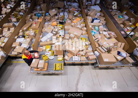 Colonia, Germania. 12 ottobre 2021. Un conducente di consegna pacchi ordina e mette i pacchi in un veicolo di consegna presso una base di consegna DHL Deutsche Post. Credit: Rolf Vennenbernd/dpa/Alamy Live News Foto Stock