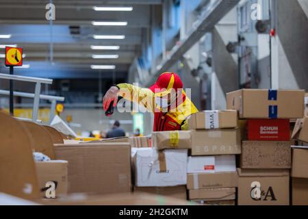 Colonia, Germania. 12 ottobre 2021. Un conducente di consegna pacchi ordina e mette i pacchi in un veicolo di consegna presso una base di consegna DHL Deutsche Post. Credit: Rolf Vennenbernd/dpa/Alamy Live News Foto Stock