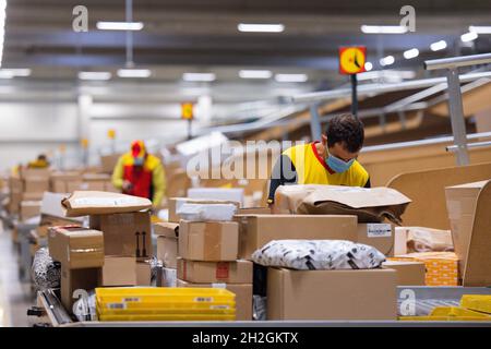 Colonia, Germania. 12 ottobre 2021. Il personale addetto alla consegna dei pacchi smistano e mette i pacchi in un veicolo di consegna presso una base di consegna DHL Deutsche Post. Credit: Rolf Vennenbernd/dpa/Alamy Live News Foto Stock