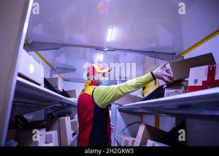 Colonia, Germania. 12 ottobre 2021. Un conducente di consegna pacchi ordina e mette i pacchi in un veicolo di consegna presso una base di consegna DHL Deutsche Post. Credit: Rolf Vennenbernd/dpa/Alamy Live News Foto Stock