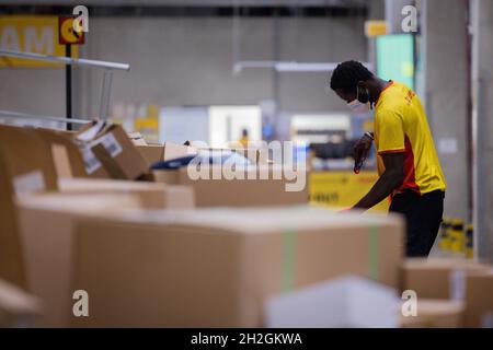 Colonia, Germania. 12 ottobre 2021. Un conducente di consegna pacchi ordina e mette i pacchi in un veicolo di consegna presso una base di consegna DHL Deutsche Post. Credit: Rolf Vennenbernd/dpa/Alamy Live News Foto Stock