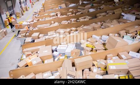 Colonia, Germania. 12 ottobre 2021. Un conducente di consegna pacchi ordina e mette i pacchi in un veicolo di consegna presso una base di consegna DHL Deutsche Post. Credit: Rolf Vennenbernd/dpa/Alamy Live News Foto Stock