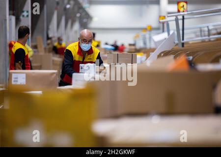 Colonia, Germania. 12 ottobre 2021. Il personale addetto alla consegna dei pacchi smistano e mette i pacchi in un veicolo di consegna presso una base di consegna DHL Deutsche Post. Credit: Rolf Vennenbernd/dpa/Alamy Live News Foto Stock