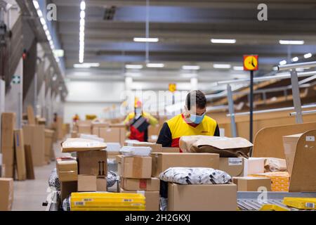 Colonia, Germania. 12 ottobre 2021. Il personale addetto alla consegna dei pacchi smistano e mette i pacchi in un veicolo di consegna presso una base di consegna DHL Deutsche Post. Credit: Rolf Vennenbernd/dpa/Alamy Live News Foto Stock