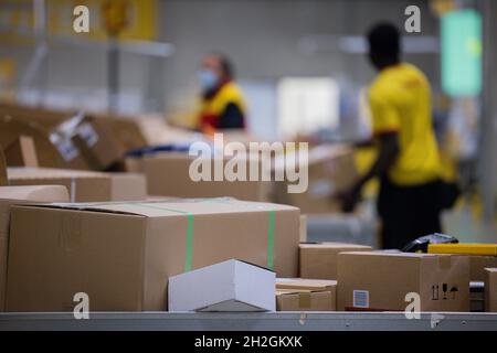 Colonia, Germania. 12 ottobre 2021. Il personale addetto alla consegna dei pacchi smistano e mette i pacchi in un veicolo di consegna presso una base di consegna DHL Deutsche Post. Credit: Rolf Vennenbernd/dpa/Alamy Live News Foto Stock