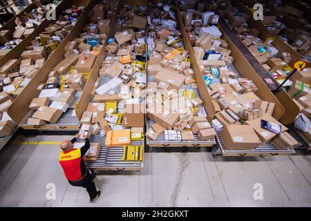 Colonia, Germania. 12 ottobre 2021. Un conducente di consegna pacchi ordina e mette i pacchi in un veicolo di consegna presso una base di consegna DHL Deutsche Post. Credit: Rolf Vennenbernd/dpa/Alamy Live News Foto Stock