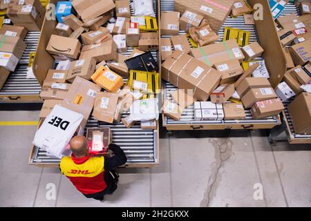 Colonia, Germania. 12 ottobre 2021. Un conducente di consegna pacchi ordina e mette i pacchi in un veicolo di consegna presso una base di consegna DHL Deutsche Post. Credit: Rolf Vennenbernd/dpa/Alamy Live News Foto Stock