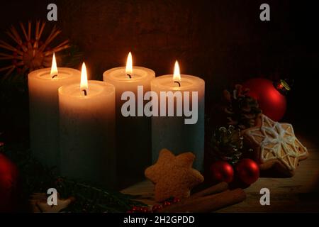 Quattro candele accese per l'avvento, decorazione di Natale e biscotti di pan di zenzero su uno sfondo rustico marrone scuro, spazio copia, fuoco selezionato, narr Foto Stock