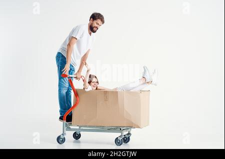 una giovane coppia cavalcare un carrello intrattenimento sfondo chiaro Foto Stock