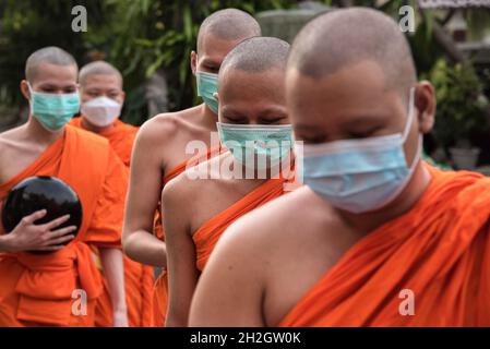 Bangkok, Tailandia. 22 ottobre 2021. I monaci buddisti thailandesi indossano maschere per il viso viste durante la fine della cerimonia della Quaresima buddista al Wat Saket. Il giorno della Quaresima buddista è un giorno di significato religioso per i devoti buddisti e segna l'inizio del periodo di tre mesi, In cui tutti i monaci dovrebbero rimanere nei loro templi e non viaggiare da nessuna parte, il giorno della Quaresima buddista in Thailandia ha iniziato il 25 luglio 2021 e termina il 21 ottobre 2021, quando i devoti buddisti si uniscono al merito per celebrare il ritorno del Signore Buddha sulla terra. Credit: SOPA Images Limited/Alamy Live News Foto Stock