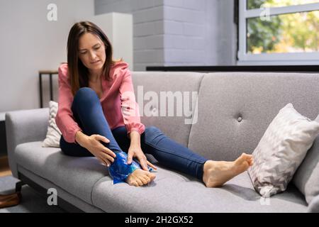 Donna che tiene gling gel terapia Pack dopo lesioni alle gambe Foto Stock