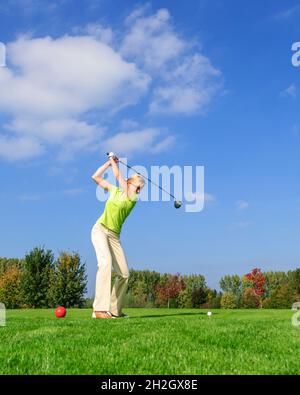 Attraente giocatore di golf femminile che colpisce la palla dal tee Foto Stock