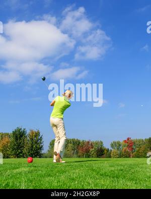 Attraente giocatore di golf femminile che colpisce la palla dal tee Foto Stock