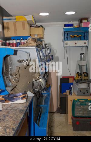 Giovane calzolaio che menda le calzature in officina. Foto Stock