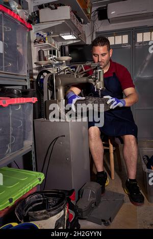 Giovane calzolaio che menda le calzature in officina. Foto Stock