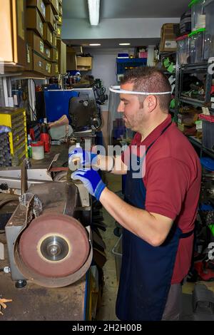 Giovane calzolaio che menda le calzature in officina. Foto Stock