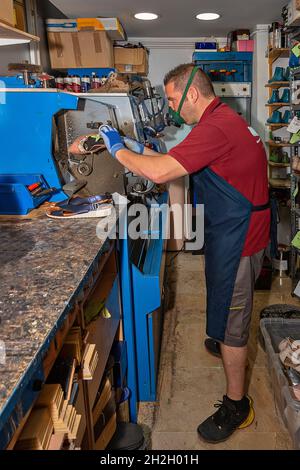 Giovane calzolaio che menda le calzature in officina. Foto Stock