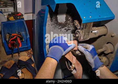 Giovane calzolaio che menda le calzature in officina. Foto Stock