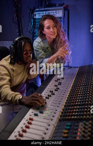 Giovane coppia che usa la tastiera musicale per registrare una canzone nello studio di registrazione Foto Stock