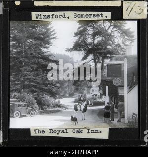 Royal Oak inn, Halse Lane, Winsford, West Somerset, Somerset, 1927-1939. Una donna su un cavallo su Halse Lane guardò tre persone e un cane fuori dal Royal Oak Inn. La didascalia in questa diapositiva recita: "Winsford, Somerset, The Royal Oak Inn." Il Royal Oak Inn faceva parte della tenuta Acland fino al 1926. All'asta della tenuta, la locanda è stata acquisita dalla People's rinfreschi Houses Association, il cui segno può essere visto sulla sinistra di questa fotografia. Foto Stock