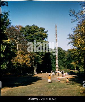 Totem Pole, Windsor Great Park, Runnymede, Surrey, 1959. Il Totem Pole nel Windsor Great Park, visto da sud-ovest, con persone riunite intorno ad esso. Il totem pole nel Windsor Great Park è stato presentato alla Regina Elisabetta II nel giugno 1958 dal capo Mungo Martin del Kwakiutl o Kwakwaka'wakw o Kwakiutl. Il palo è alto 100 piedi e segna il centenario della Columbia Britannica, che è stata proclamata una colonia della Corona nel 1858 dalla Regina Vittoria. Un albero di 600 anni è stato abbattuto per creare il palo, che è stato scolpito dal capo Mungo Martin. Un secondo, identico polo totem è stato scolpito e rimane in V Foto Stock