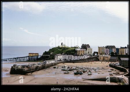 Tenby Harbour, Tenby, Pembrokeshire, Galles, 1964. Tenby Harbour a bassa marea, in cui le barche sono affogate, con Castle Hill e case dipinte di colore su Bridge Street e Pier Hill Foto Stock