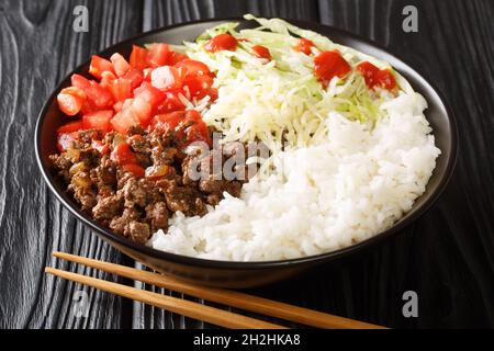 Riso giapponese taco con macinato di manzo, verdure, formaggio e salsa primo piano in una ciotola sul tavolo. Orizzontale Foto Stock