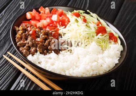 Il takoraisu di riso Taco è un esempio popolare di cucina Okinawan che consiste di manzo macinato al gusto di taco servito su un letto di riso da vicino in una ciotola sul th Foto Stock