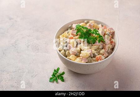 Insalata Olivier con verdure, salsiccia e maionese su sfondo chiaro. Insalata tradizionale russa. Foto Stock