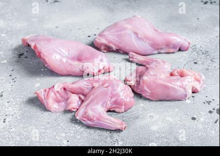 Le gambe di coniglio crudo affettano su un macellaio. Sfondo grigio. Vista dall'alto Foto Stock