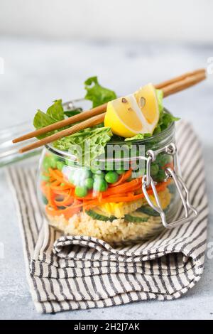 Vaso in vetro con verdure fresche crude e couscous groats. Prep pasto sano - foto di preparazione ricetta. Piatti vegani sani in contenitori di vetro. Weig Foto Stock