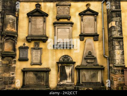 Parete gialla di Greyfriar's Kirk, Edimburgo, Scozia, Regno Unito fiancheggiata da tombe commemorative e lapidi intagliate e storiche Foto Stock