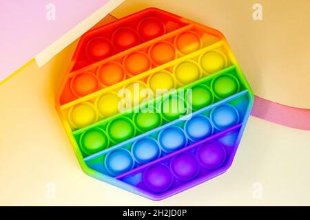 Vista dall'alto di un semplice e trendy dimple o di un giocattolo sensoriale per bambini su sfondo di carta brillante. Popolare antistress silicone bambini bolla fidget in pioggia Foto Stock