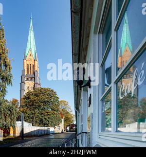 Schleswig, Germania. 22 ottobre 2021. Cattedrale di Schleswig riflessa in una finestra della città vecchia. La riapertura della Cattedrale di San Pietro dello Schleswig dopo quasi quattro anni di ristrutturazione sarà celebrata il 24 ottobre 2021 con un servizio festivo, una reception e un concerto. Per la prima volta, le campane della cattedrale suoneranno di nuovo e il grande organo risuonerà. Credit: Markus Scholz/dpa/Alamy Live News Foto Stock