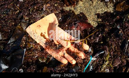 Un vecchio guanto di gomma che inquina una spiaggia sabbiosa - John Gollop Foto Stock