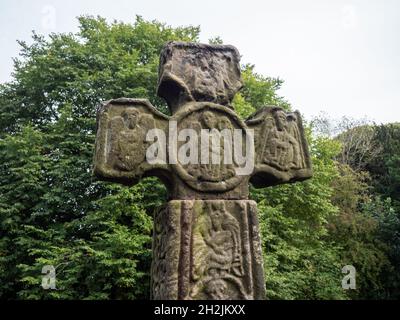 Un vecchio Saxon Cross, probabilmente del IX secolo, nel sagrato della chiesa di San Lorenzo, Eyam, Derbyshire, Regno Unito Foto Stock