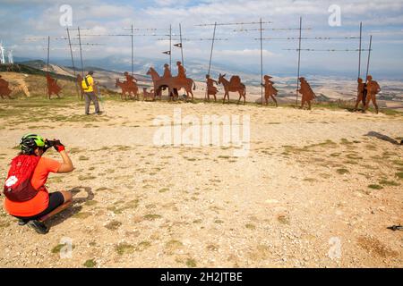 Pellegrini a piedi il Camino de Santiago la via di San Giacomo sull'Alto del Perdon sopra Pamplona Navarra Spagna guardando le sculture in acciaio pellegrino Foto Stock