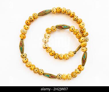 collana vintage con osso intagliato e perle in ottone intarsiato su carta bianca Foto Stock